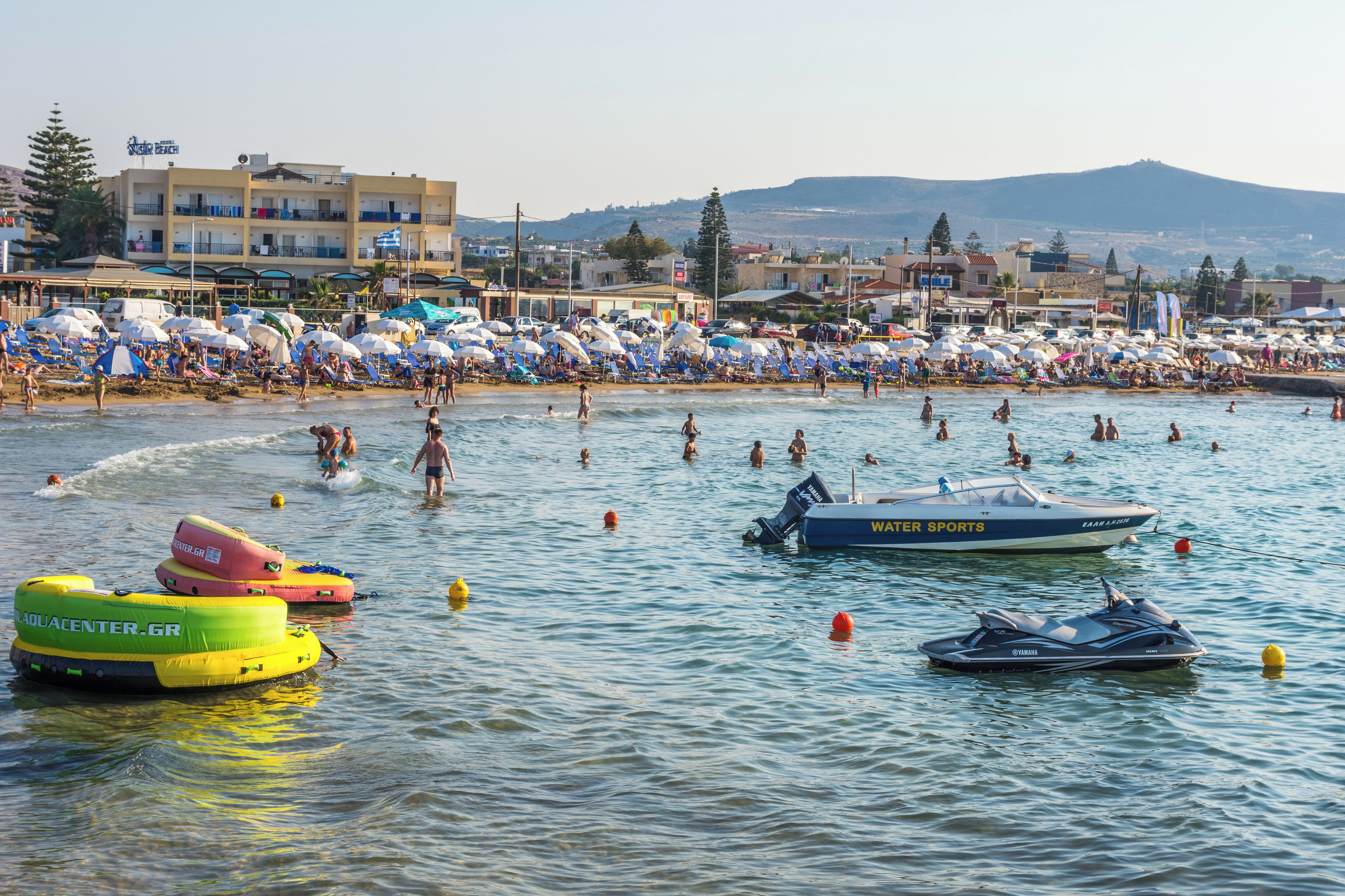 A beach with multiple watercraft and beach umbrellas.