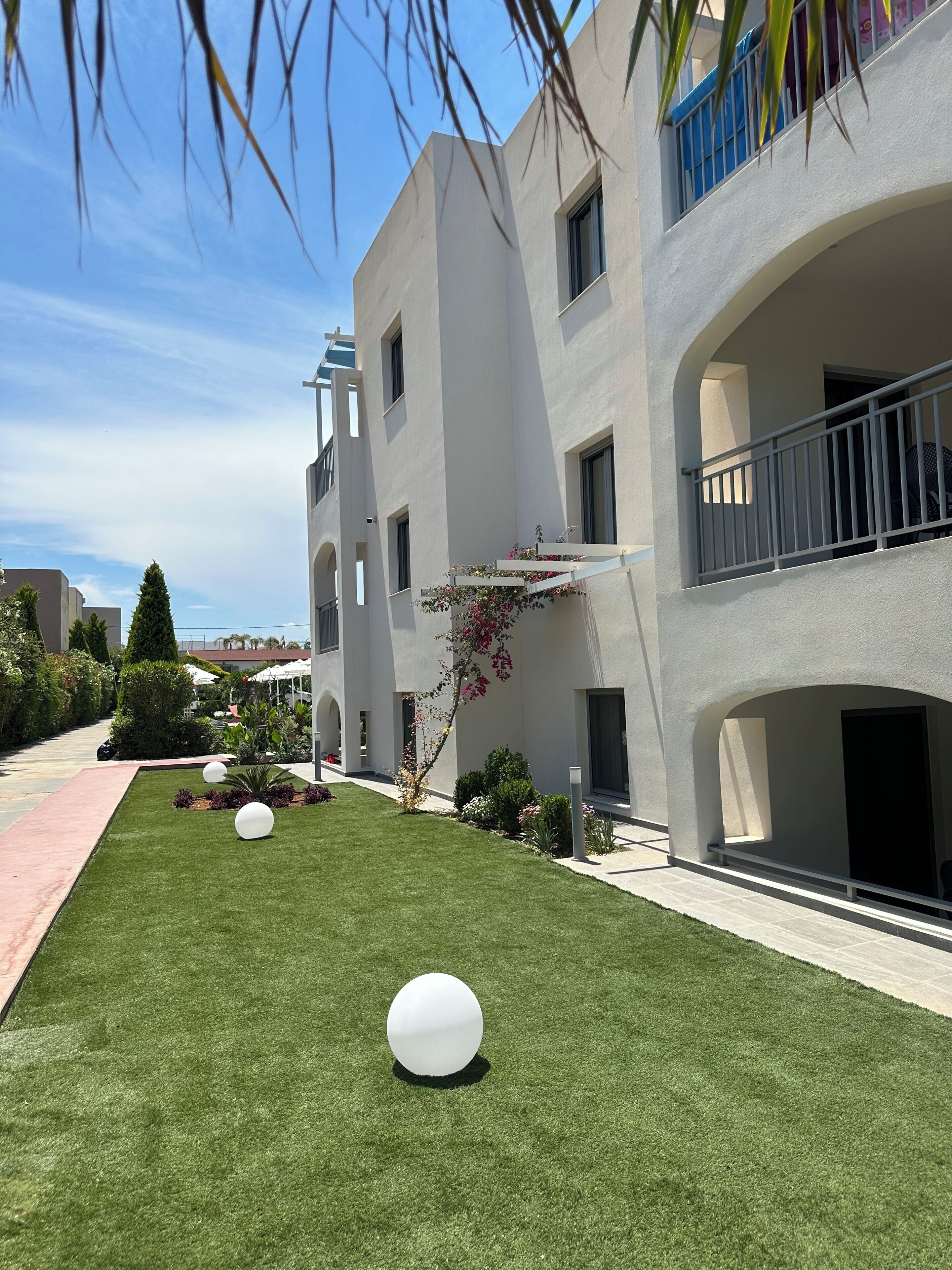 A modern building with balconies, a well-maintained lawn, and spherical decorative elements.