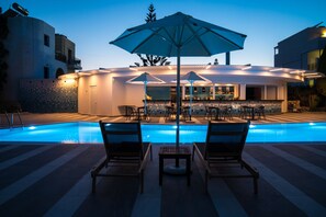 Ein Poolbereich mit Liegestühlen, Sonnenschirmen und einer Bar.