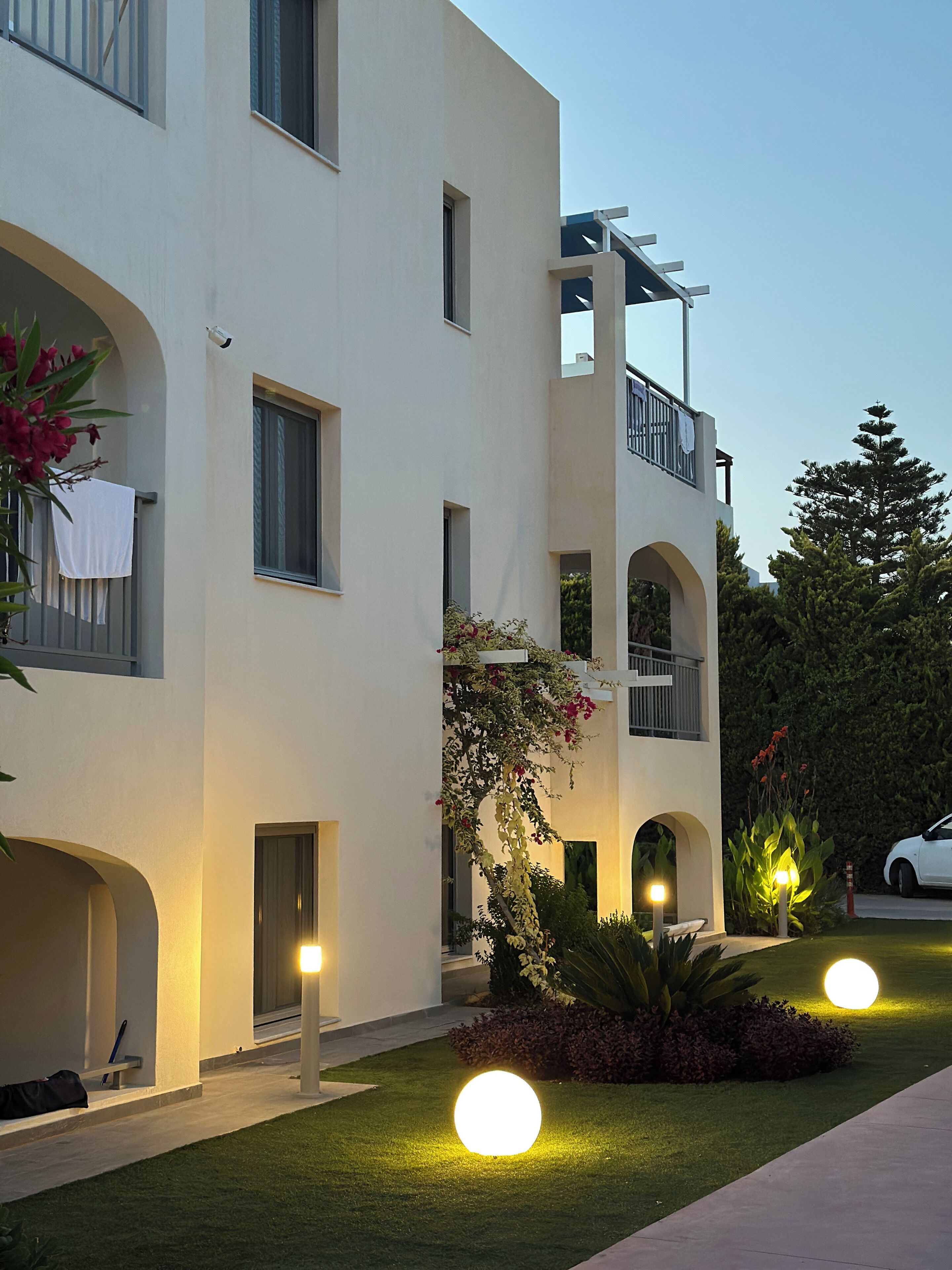 A multi-story building with balconies, a well-maintained lawn, and outdoor lighting.