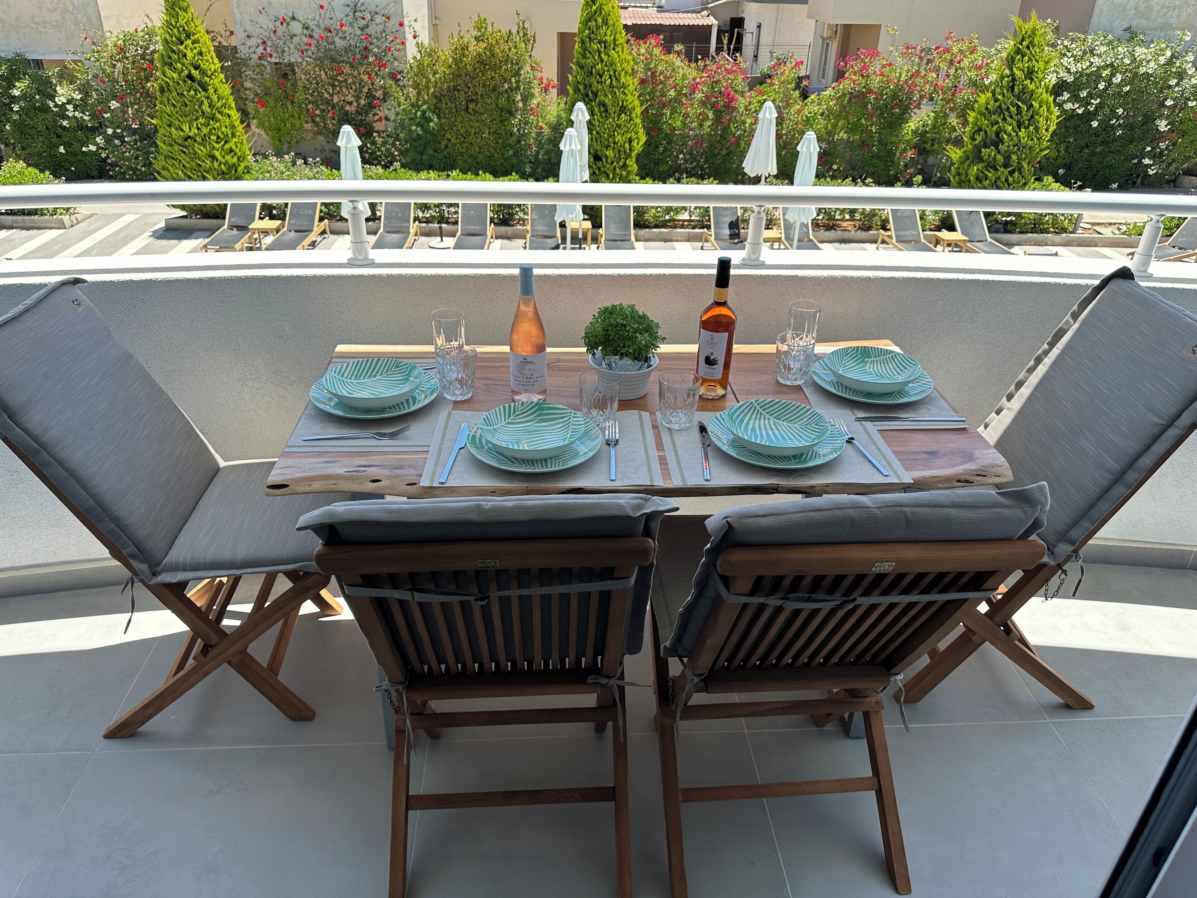 A dining area with a table set for two, featuring green leaf-patterned plates, a bottle of wine, and a small potted plant.