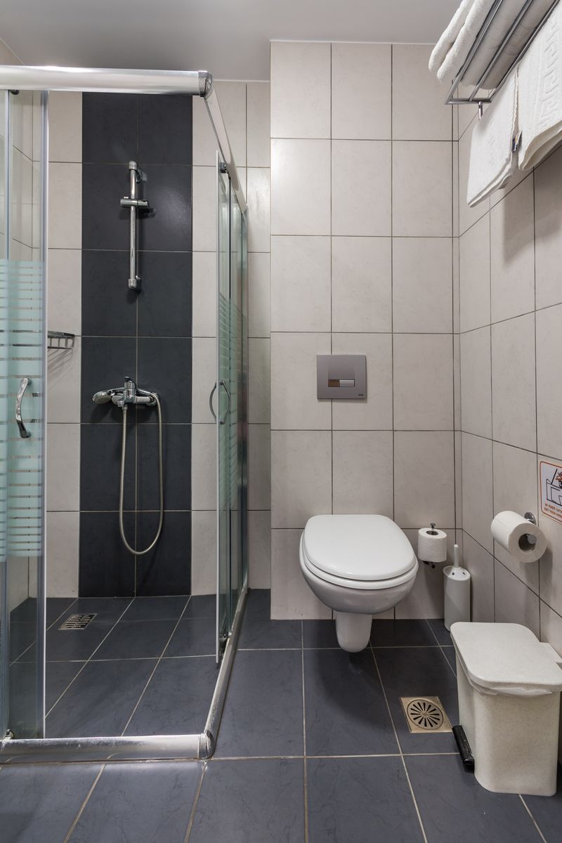 A modern bathroom with a glass-enclosed shower, a toilet, and a bidet.