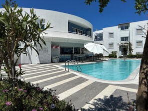 A pool area with a bar, lounge chairs, and a covered seating area. - Evdokia Suites (Hersonissos)