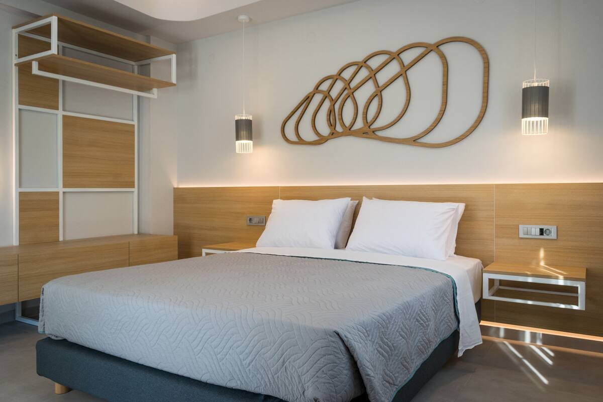 A modern bedroom with a large bed, built-in shelving, and wall-mounted lighting.