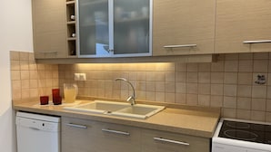 Una cocina moderna con lavavajillas Bosch, un lavatorio con un armario esmaltado arriba y una estufa Winson.