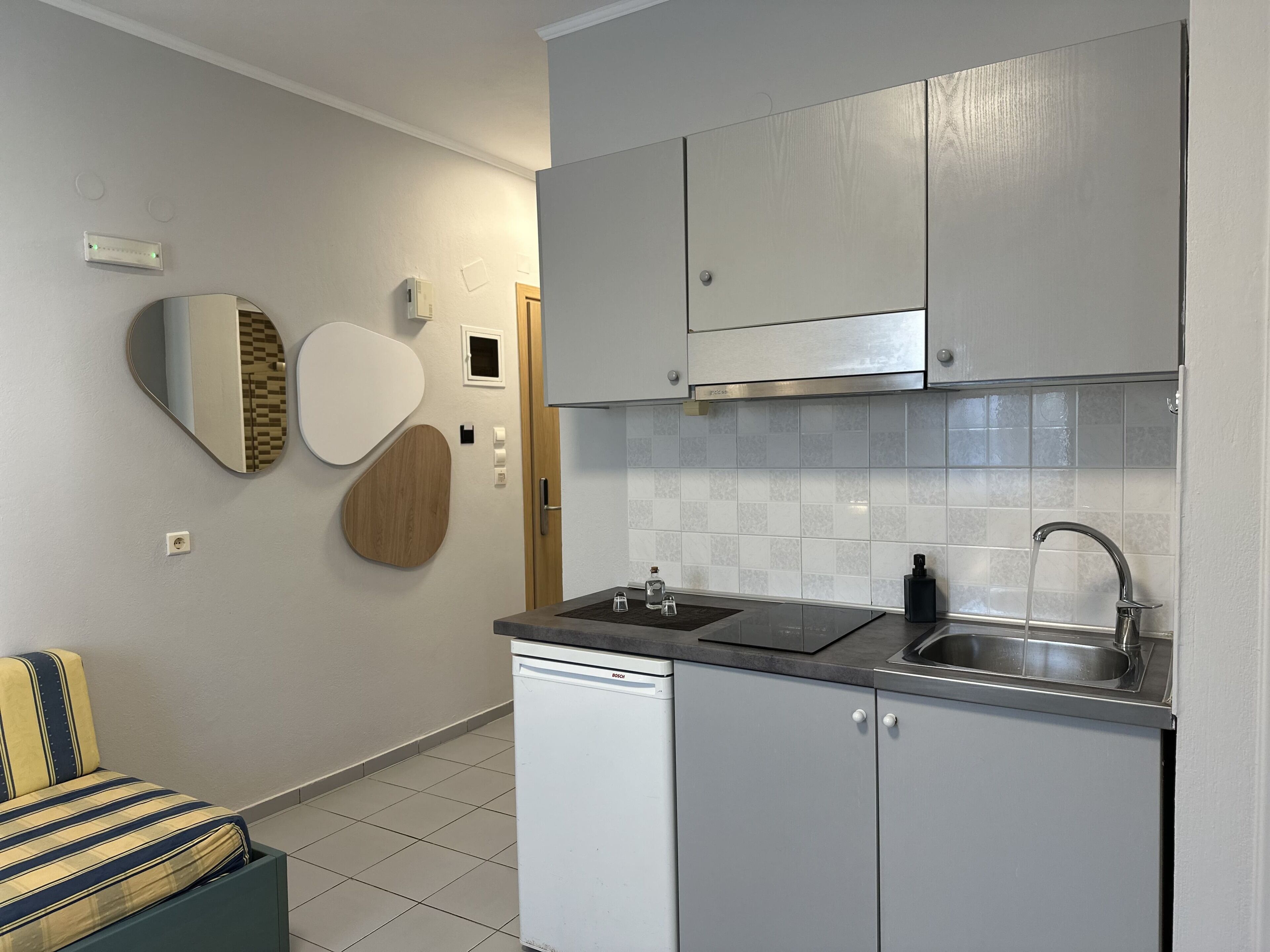 Una cucina moderna con mobili grigi, un lavello in acciaio inossidabile e una lavastoviglie integrata.