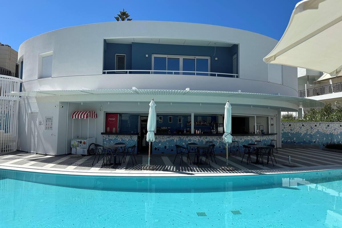 A two-story building with a pool, outdoor seating, and a Coca-Cola sign.