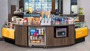 Un área de bebidas autoservicio con un refrigerador y una máquina de café.