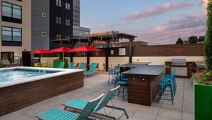 Un área de piscina en la azotea con sillones de descanso, un bar y una parrilla.