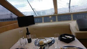 Ein Essbereich auf einem Schiff mit einem Tisch für zwei Personen, einer Weinflasche und Gläsern.