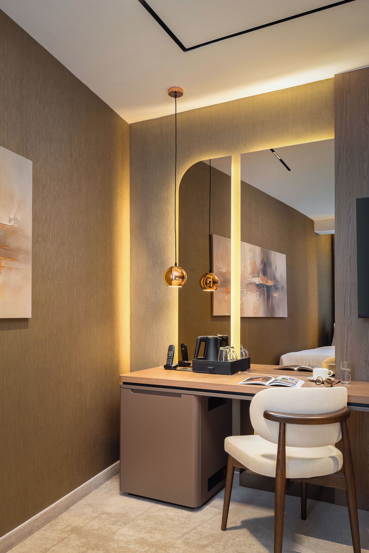 Een moderne hotelkamer met een bureau, stoel en een grote spiegel.