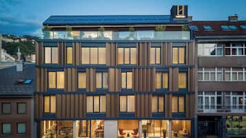 A modern hotel with a glass facade, multiple floors, and a restaurant at the ground level.