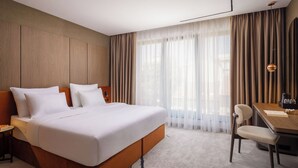 A modern hotel room with a large bed, a desk, and a chair. - PLATINUM hotel & spa (Sarajevo)