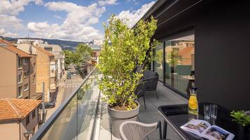 Een balkon met een bloempot, een glazen tafel met een tijdschrift en een drankje.