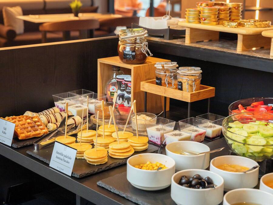 Ein reichhaltiges Buffet mit verschiedenen Speisen, darunter Waffeln, Pfannkuchen sowie eine Auswahl an Obst und Gemüse.