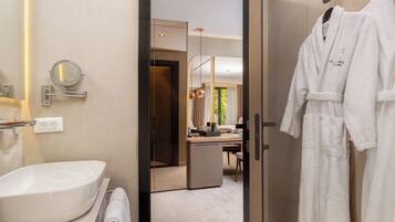 A modern bathroom with a large mirror, a sink, and a robe hanging on a hook.