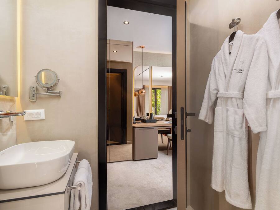 A modern bathroom with a large mirror, a sink, and a robe hanging on a hook.