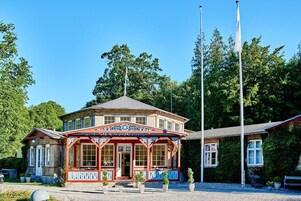 En traditionel bygning med en rød og hvid facade, en midterindgang og et flag på en stang foran.