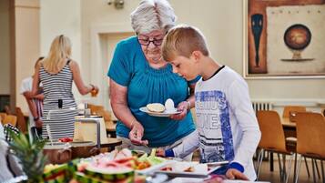 Un comedor con una barra de buffet, con diferentes alimentos y una persona sirviendo comida a otra.