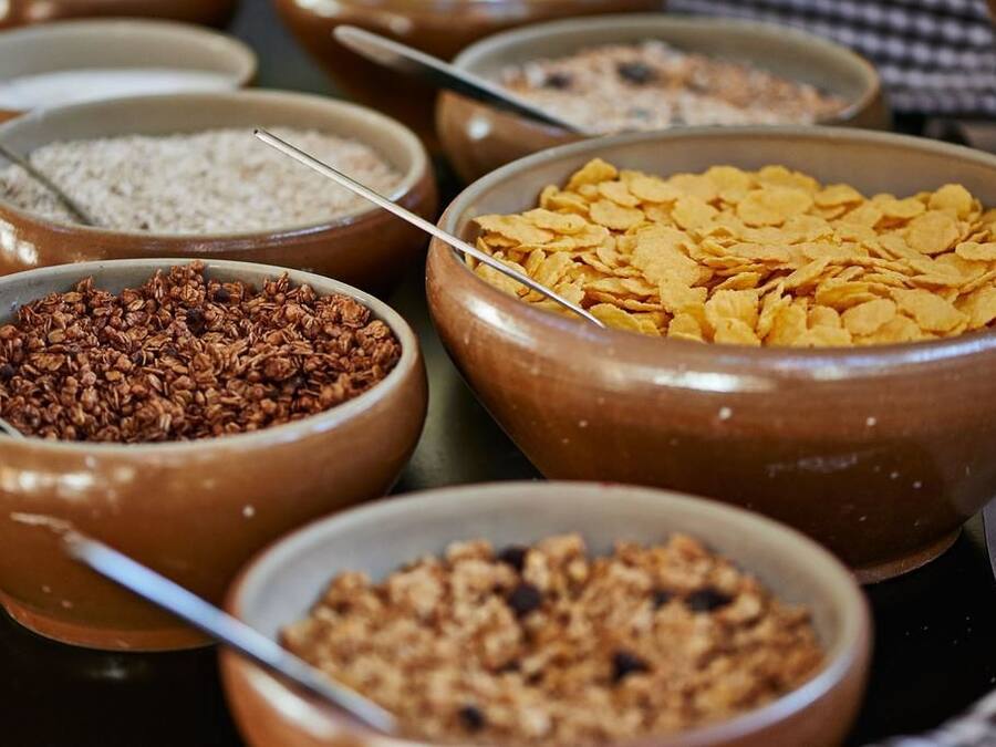 Verschiedene Speisen in Schüsseln, darunter Flocken, Granola und Getreide.