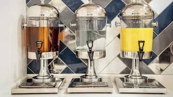 Three beverage dispensers with transparent containers and metallic bases, set against a tiled backsplash.