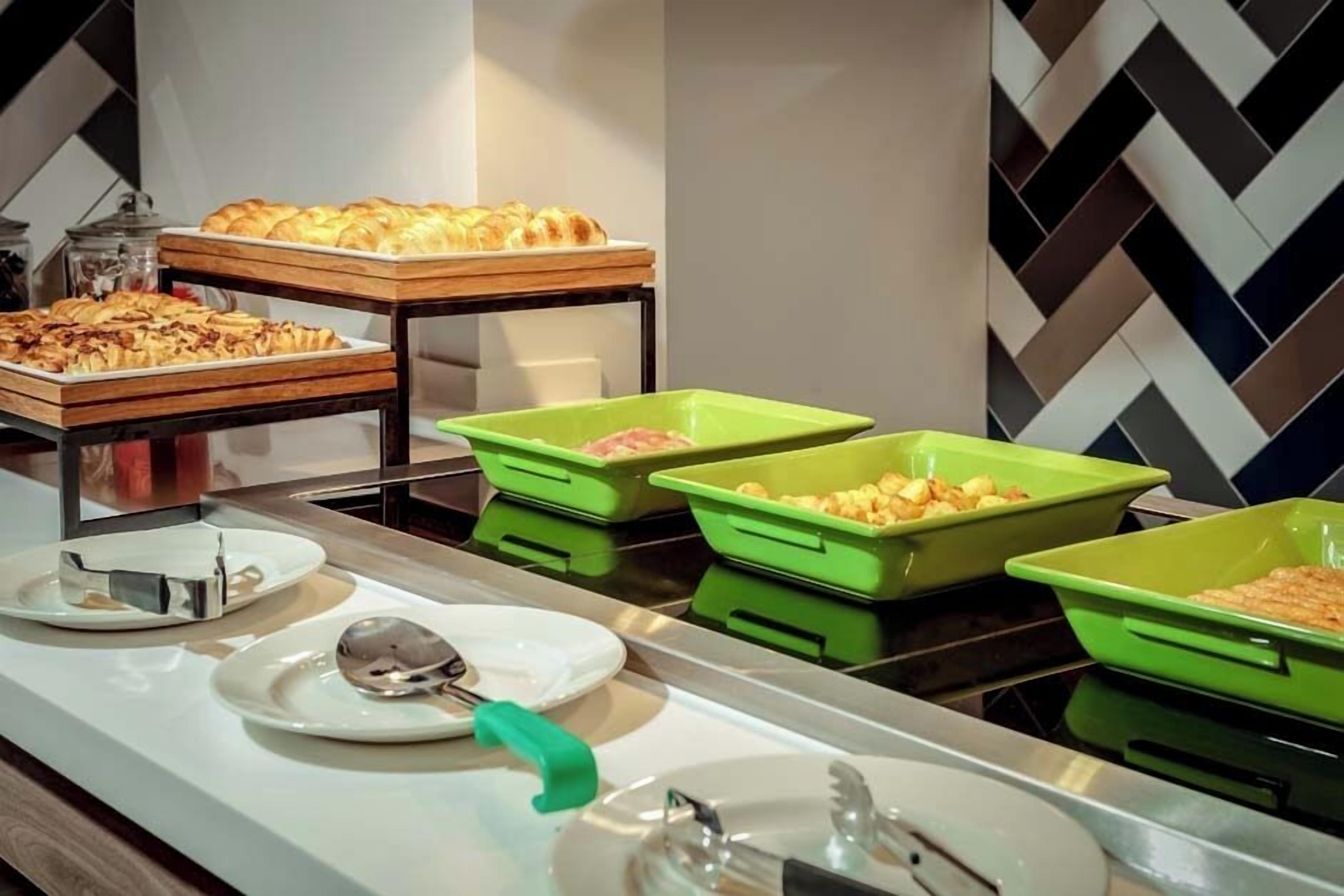 A buffet setup with various food items and serving utensils.