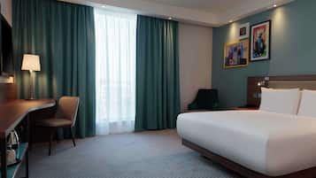 A hotel room with a bed, a desk, a chair, and a TV.