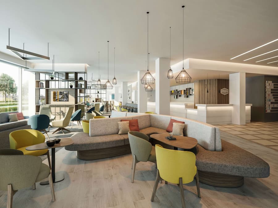 A modern hotel lobby with a sectional sofa, colorful chairs, and pendant lighting.