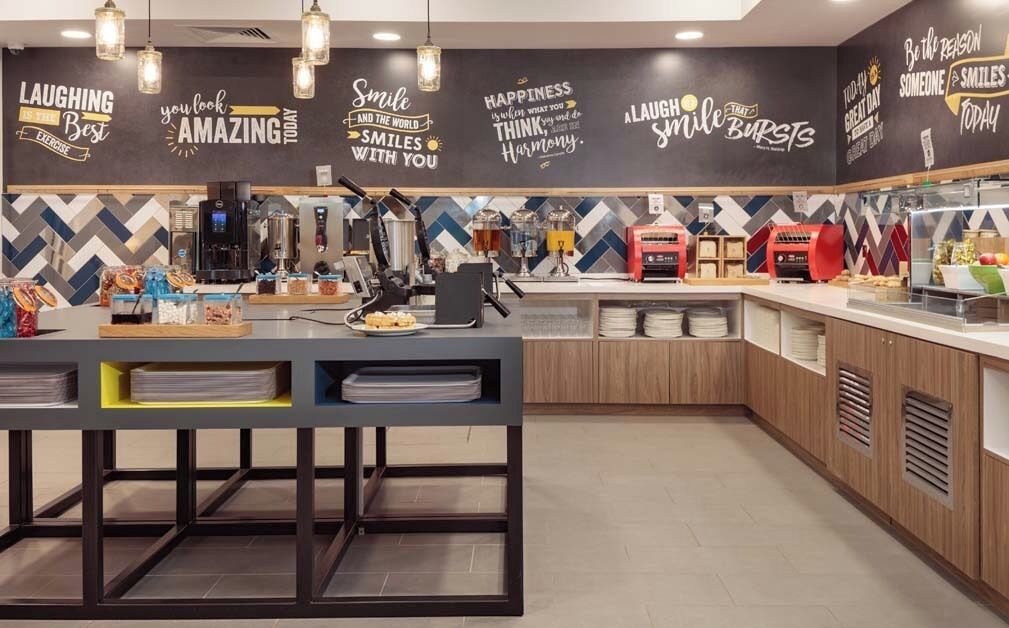En moderne caféindretning med en disk, kaffemaskiner og en væg med motiverende citater.