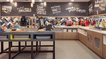 Un café moderno con interiorismo cuidado, una barra, máquinas de café y una pared decorada con citas inspiradoras.
