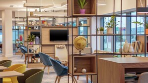 Une bibliothèque moderne dotée d’étagères en bois, de sièges confortables et de grandes fenêtres.