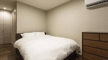 A bedroom with a bed, a dresser, and an air conditioning unit on the wall.