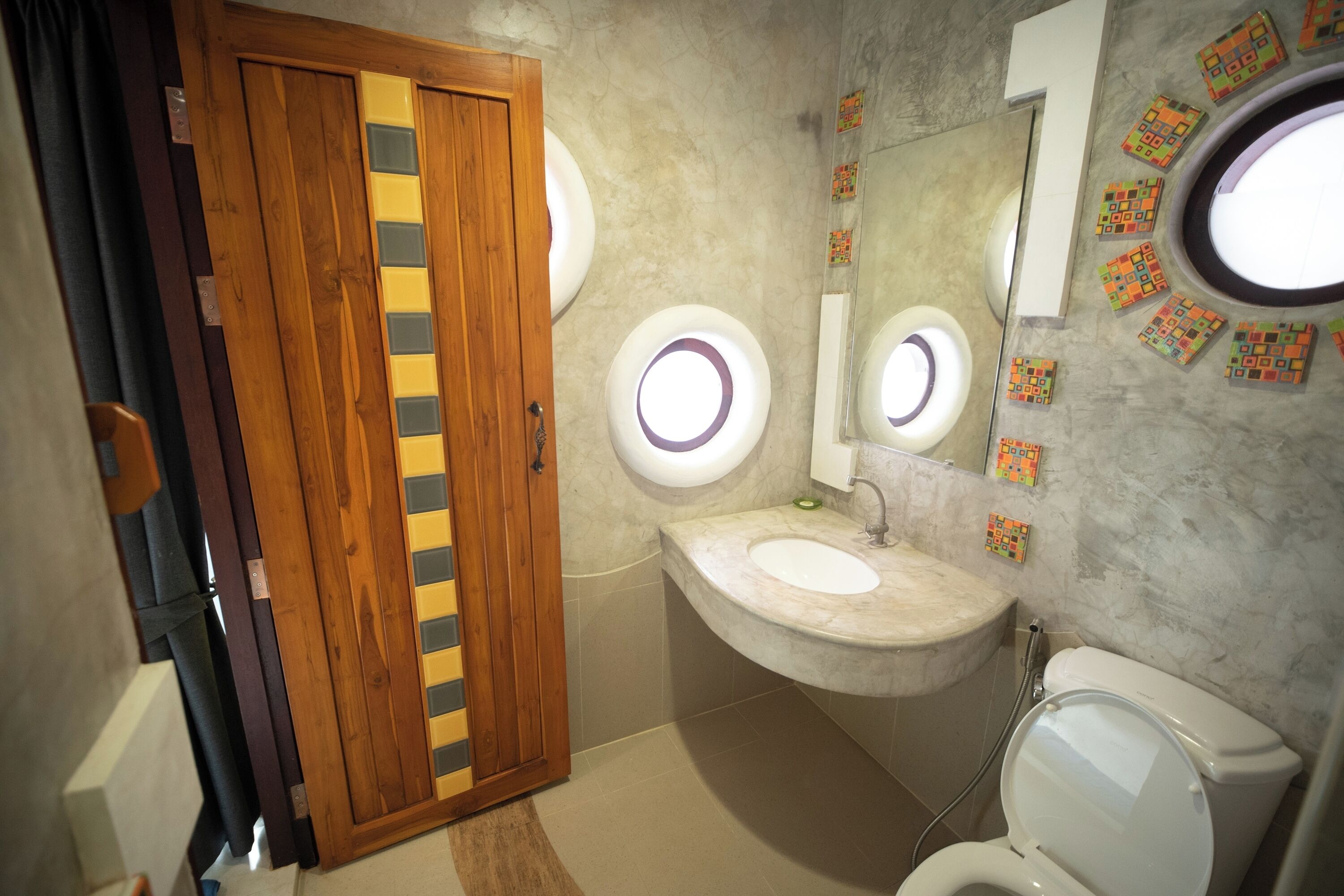 A bathroom with a wooden door, a sink with a mirror, and a toilet.