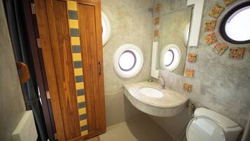 A bathroom with a wooden door, a sink with a mirror, and a toilet.