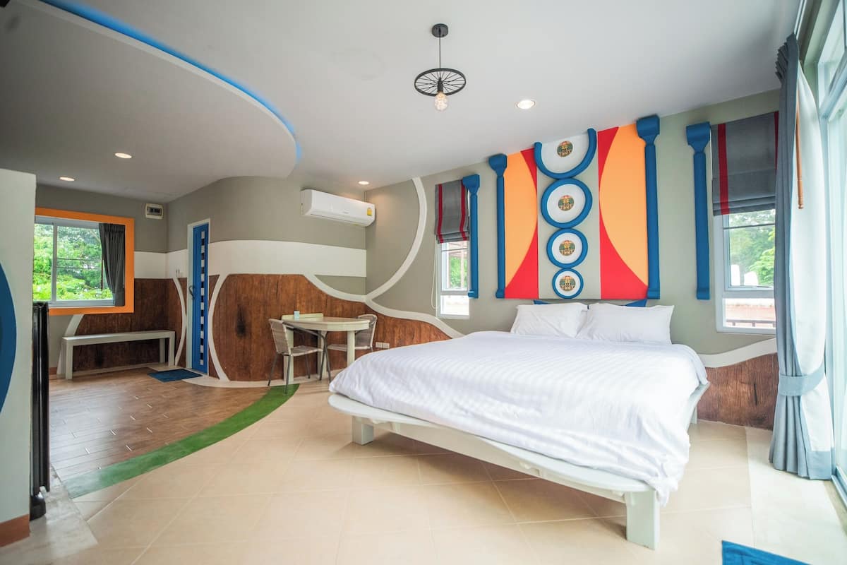Une chambre d’hôtel moderne avec un grand lit, un bureau et une vue sur la verdure.