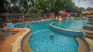 A swimming pool with a tiled edge, a slide, and inflatable toys.