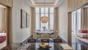 A modern hotel dining area with a marble table, a chandelier, and a view of the city through large windows.