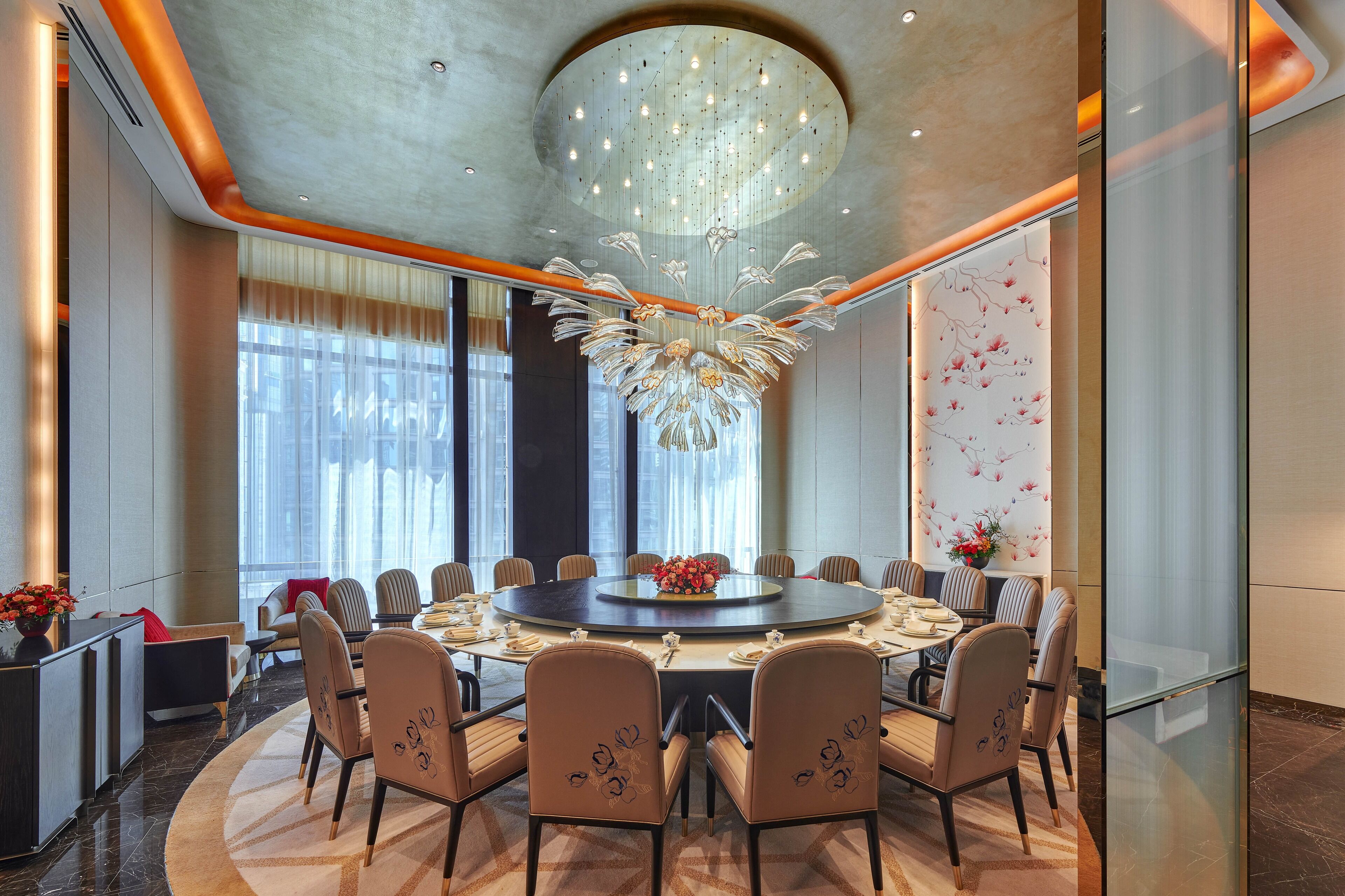 A modern conference room with a round table, comfortable chairs, and a decorative chandelier.