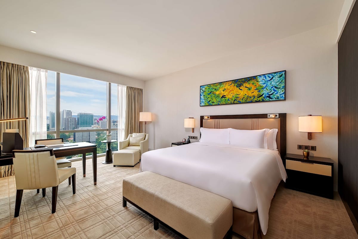 Une chambre d’hôtel avec un grand lit, un bureau, une chaise et une vue sur le paysage urbain.