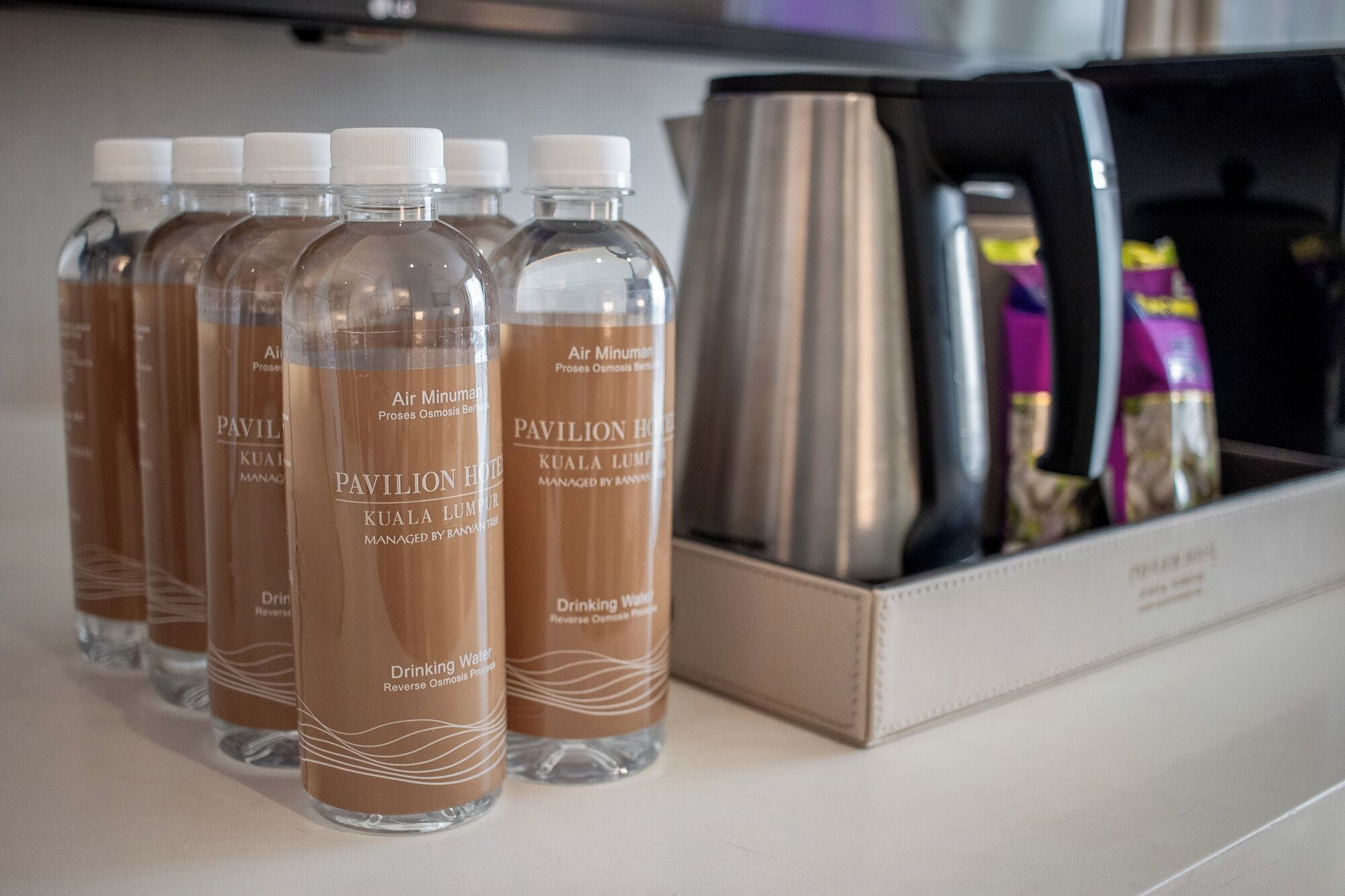Botellas de agua potable con la etiqueta 'Pavilion Hotel Kuala Lumpur' y proceso de ósmosis inversa.