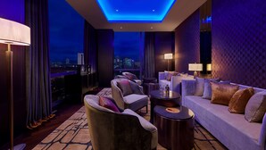 A modern hotel room with a city view, a sofa, armchairs, and a round table. - Pavilion Hotel Kuala Lumpur Managed by Banyan Tree (Kuala Lumpur)