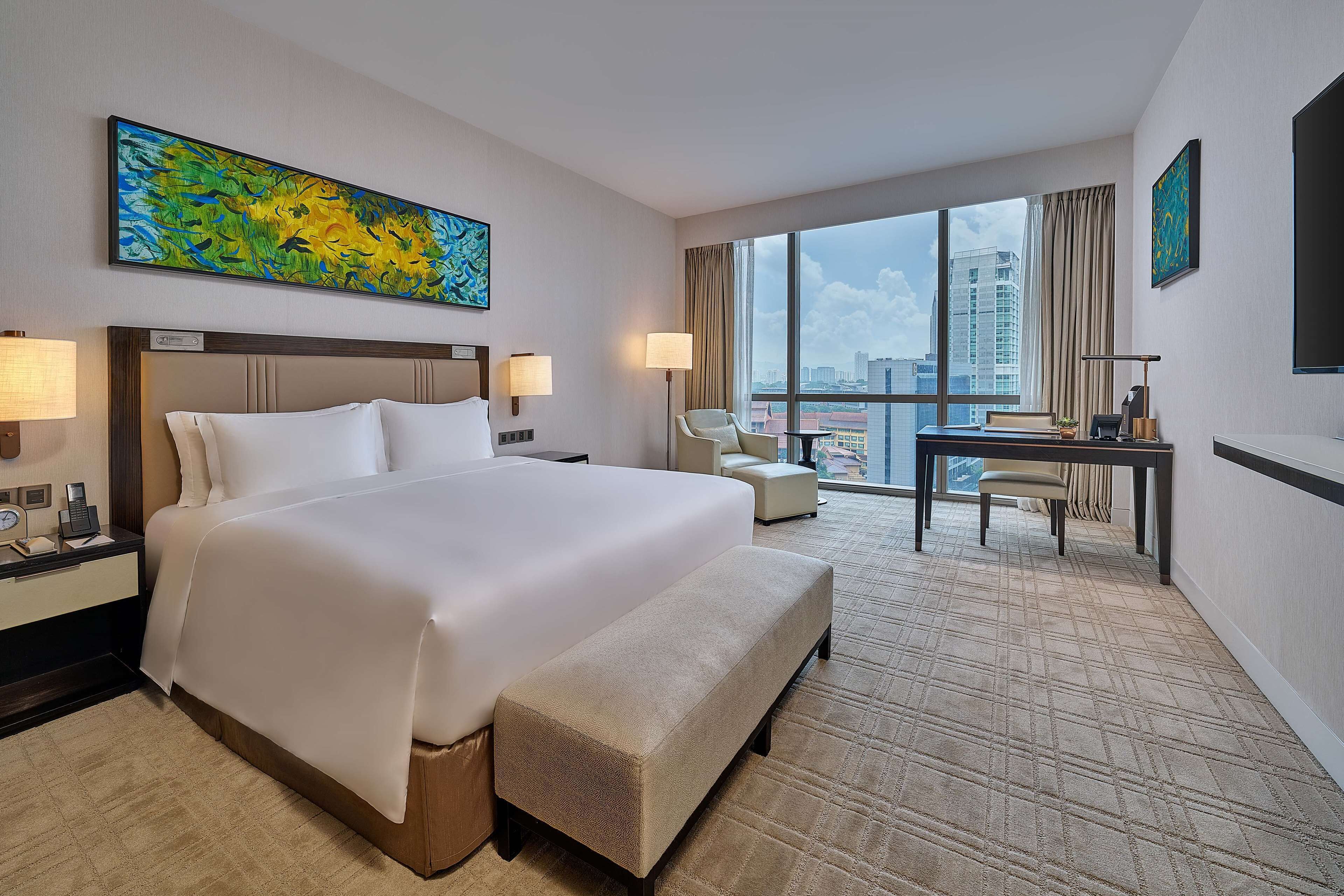 Una habitación de hotel con una cama grande, un escritorio y vistas a la ciudad.
