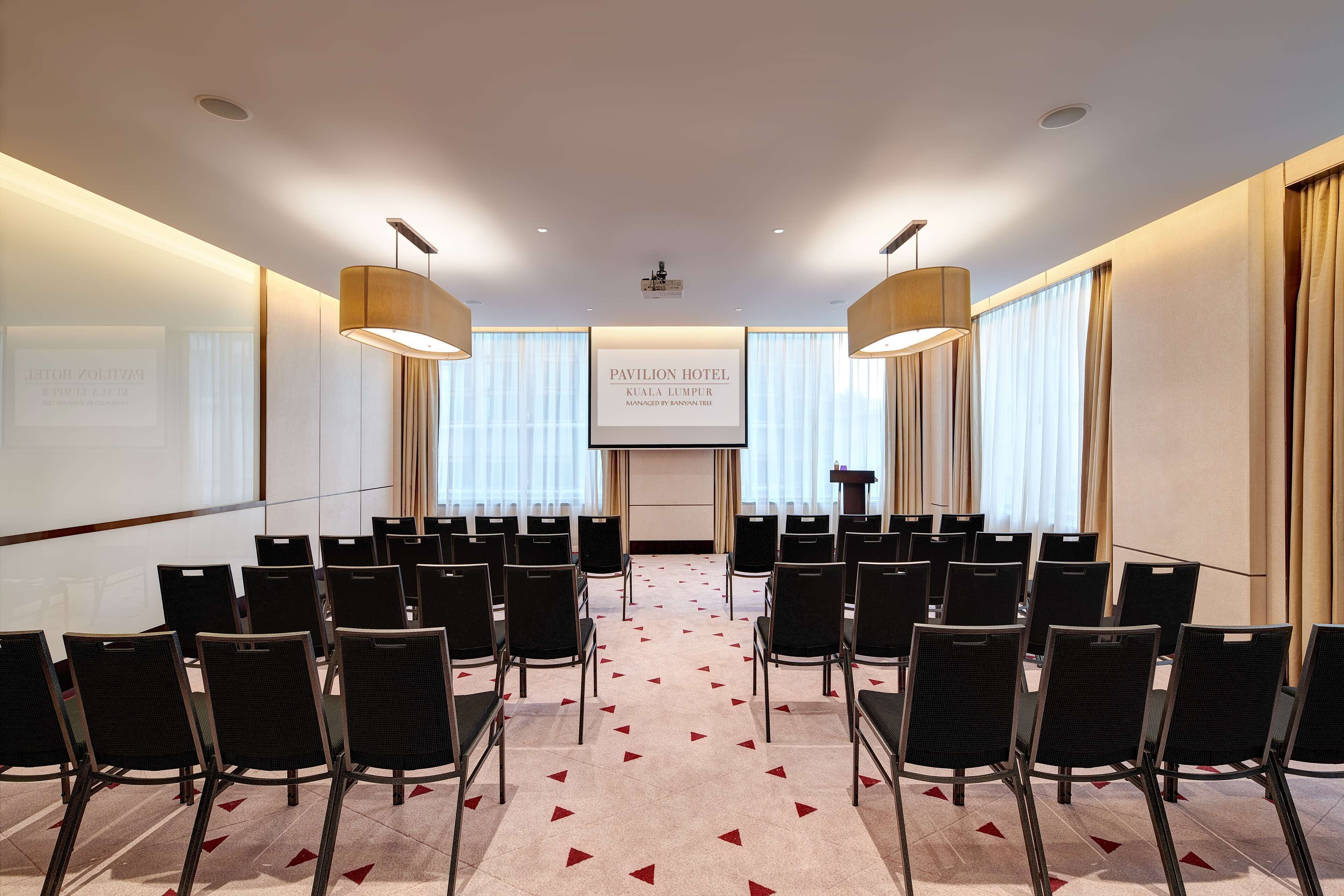 A conference room with rows of chairs, a projector screen, and a podium.