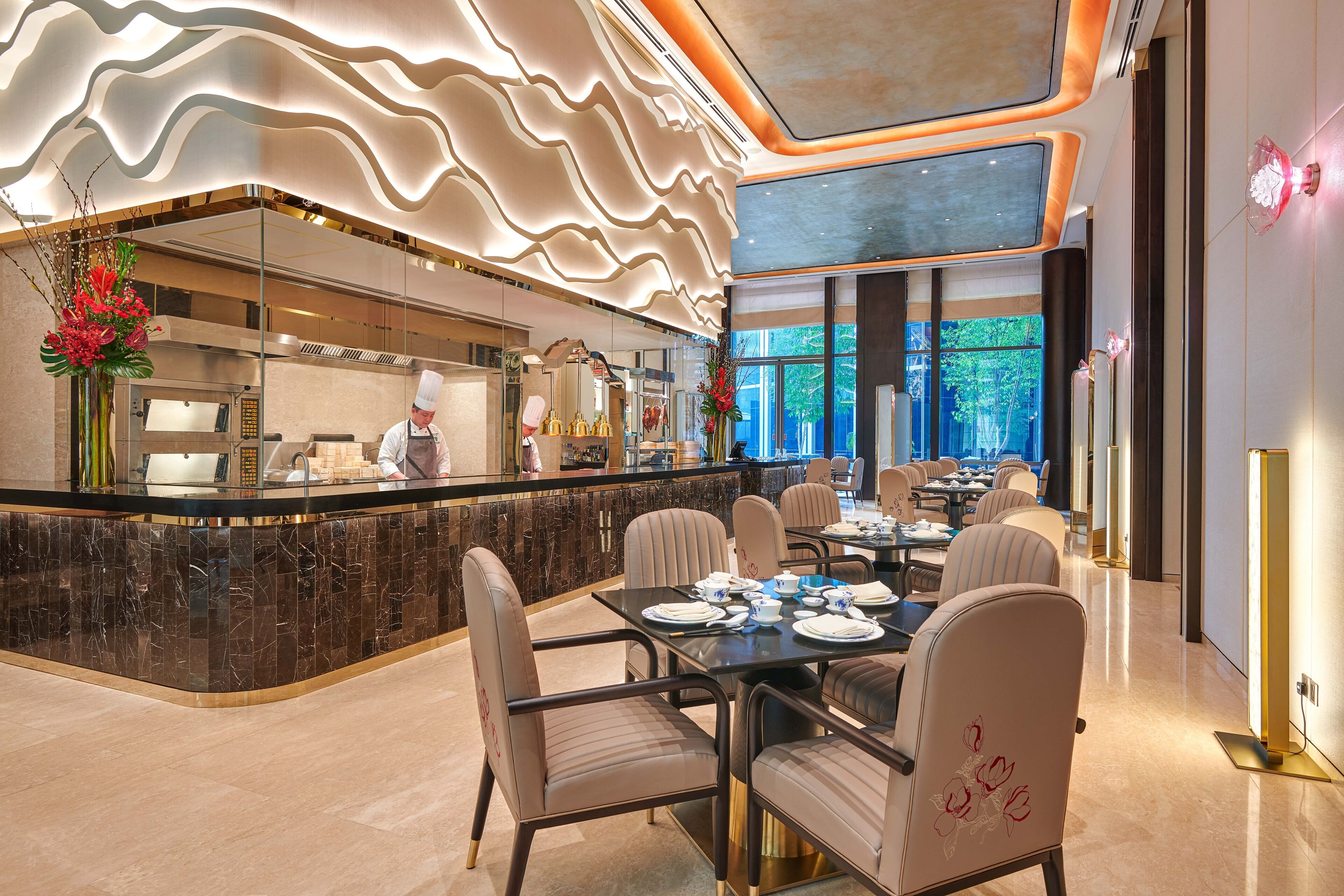 A modern restaurant with a marble counter, seating for 12, and a chef at work.