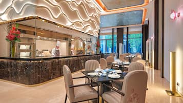 A modern restaurant with a marble counter, seating for 12, and a chef at work.