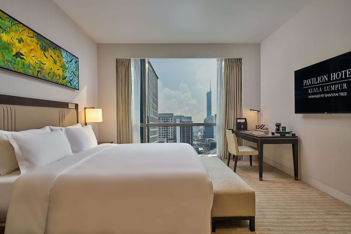 Une chambre d’hôtel avec un grand lit, un bureau et une vue sur le paysage urbain.