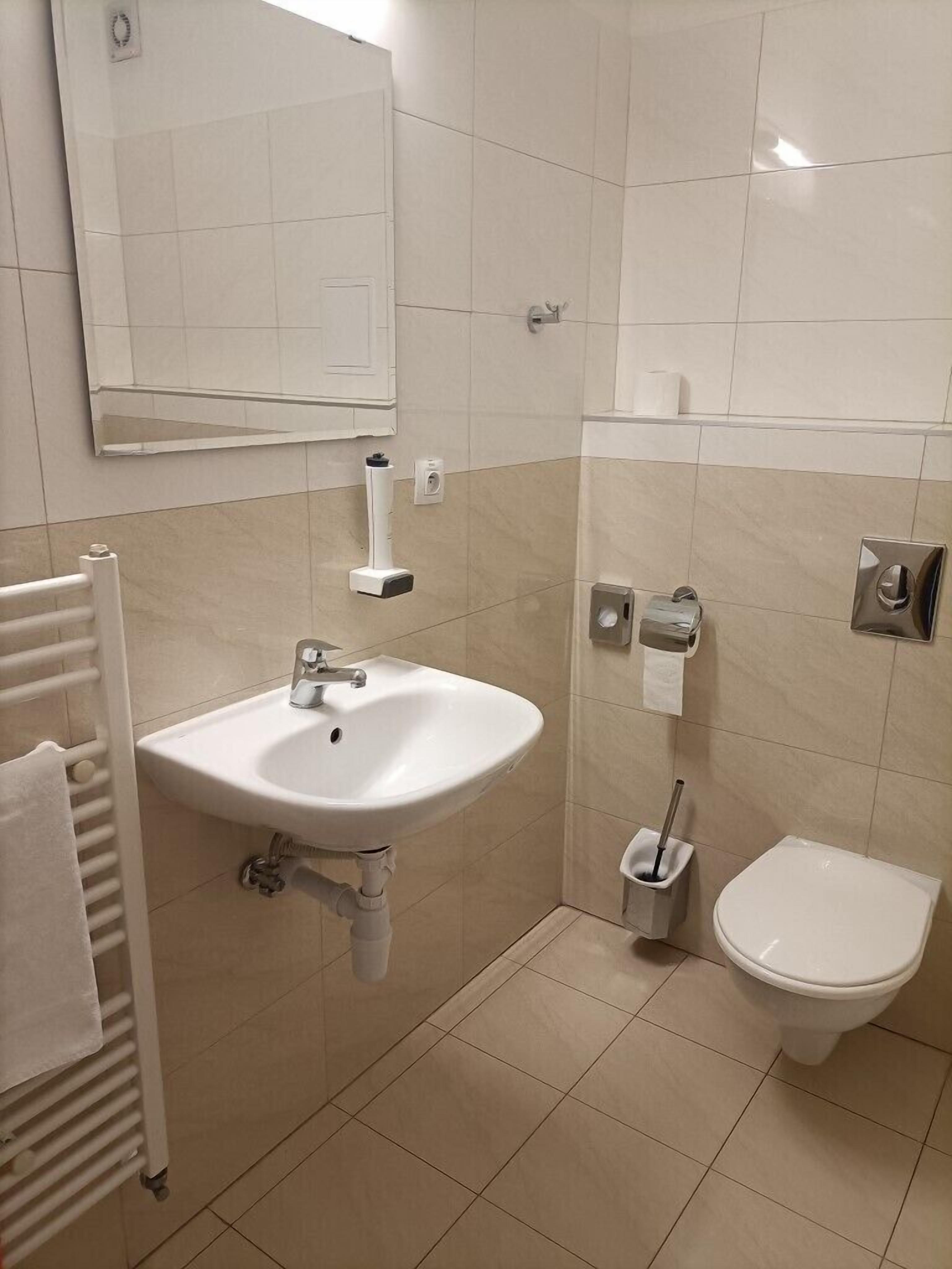 Un baño con lavamanos, inodoro y toallero.