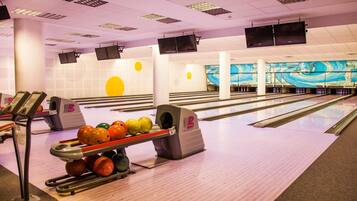 En bowlinghal med flere baner, en kugleopsamler og et muralmaleri på bagvæggen.
