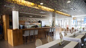 Un restaurante con barra, varias mesas y sillas.