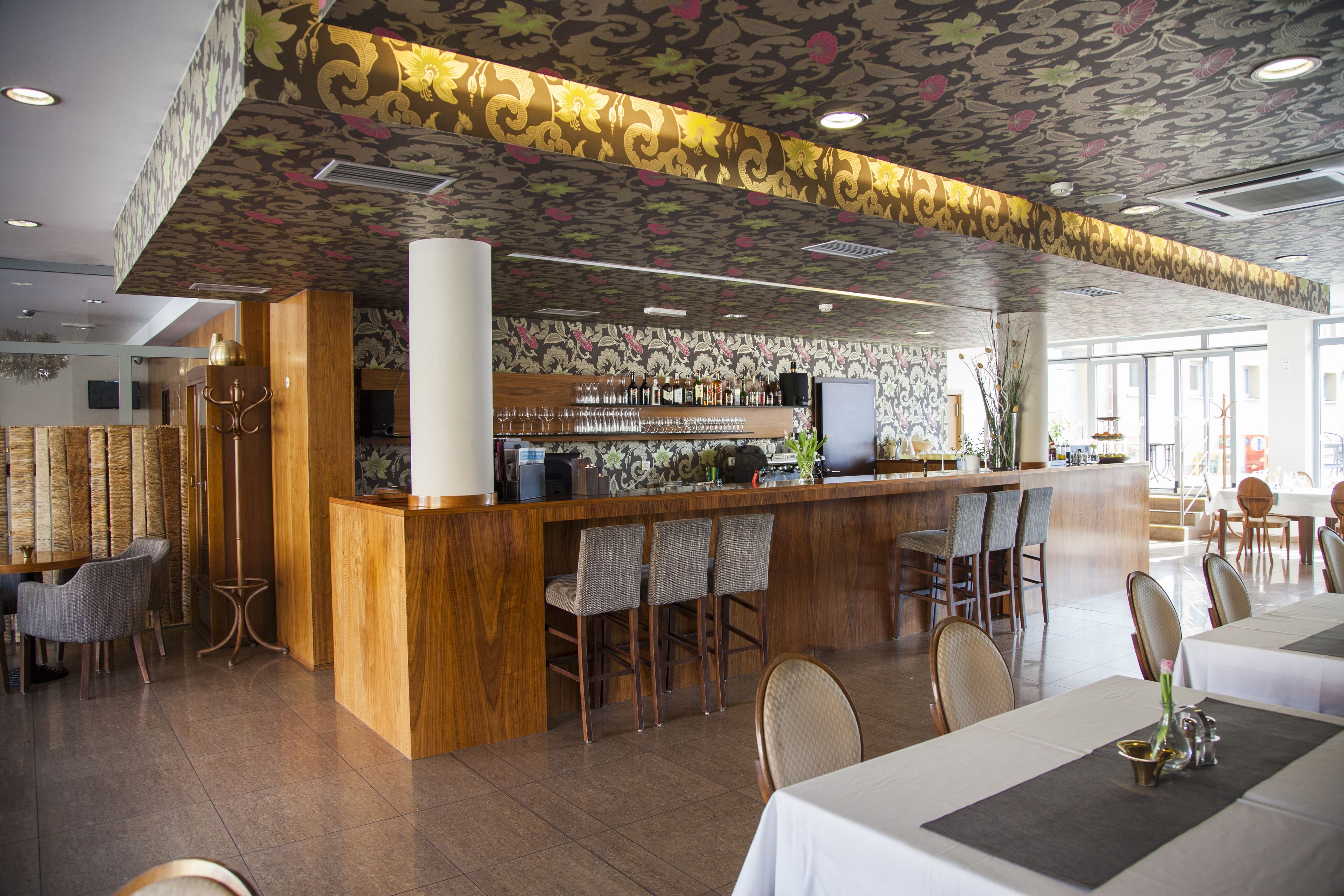 A restaurant with a bar area, wooden bar counter, and several seating options including bar stools and chairs.